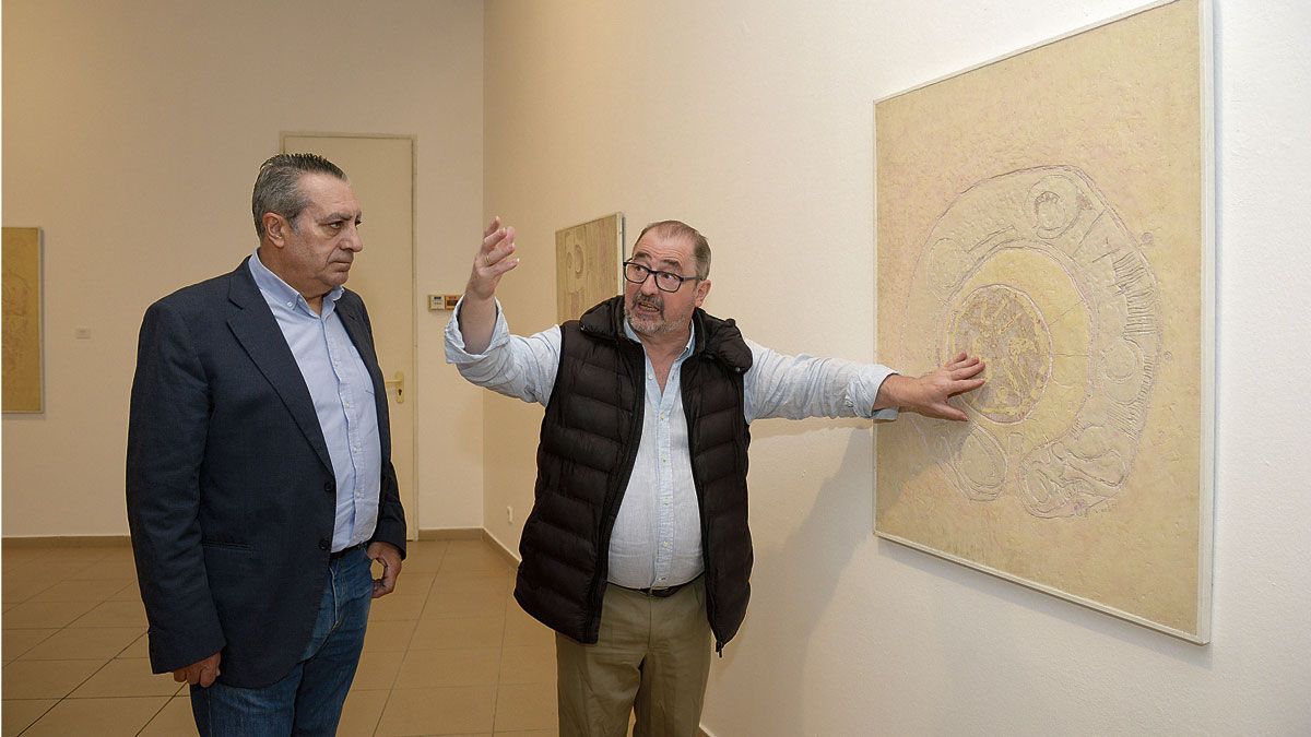Adolfo Alonso Ares y Luis García ante una de las obras que conforman la muestra retrospectiva del pintor berciano Andrés Viloria. | MAURICIO PEÑA
