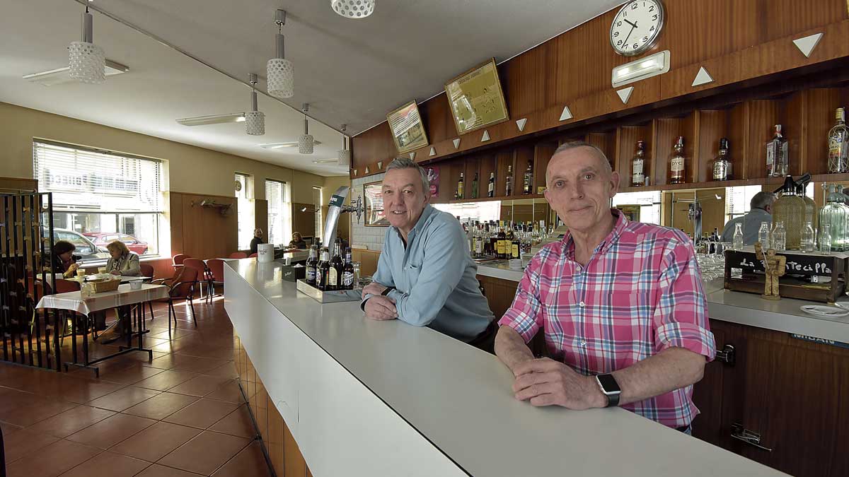 Los hermanos Luis y Teodoro González Fernández en su último día atendiendo la barra del bar La Puentecilla, en la que han estado 48 años. | SAÚL ARÉN