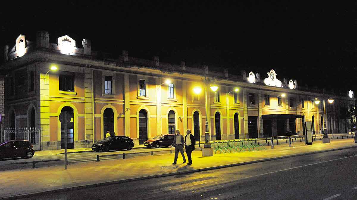 La vieja estación de tren sale de la oscuridad y, desde la noche de este sábado, vuelve a ver iluminada su fachada, sus escudos y la esfera del reloj. | DANIEL MARTÍN