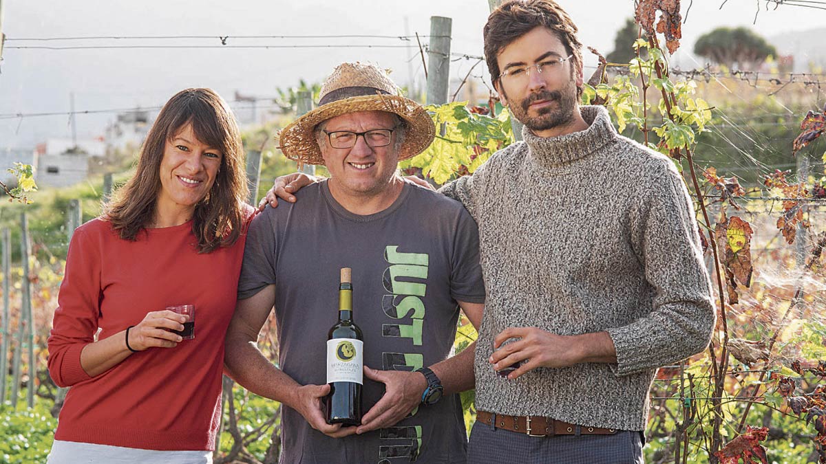 Eva Parga Dans y Pablo Alonso González posan al lado de un productor de vino natural en Canarias.