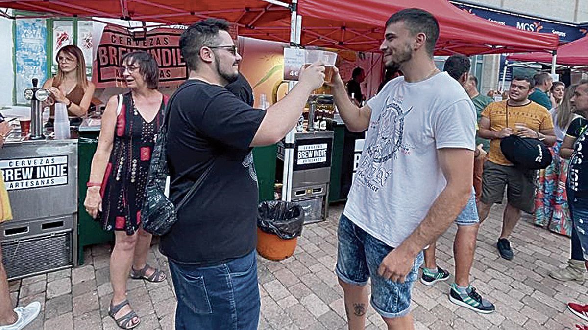 Dos amigos brindando con una cerveza fresca durante la muestra. | A. R.