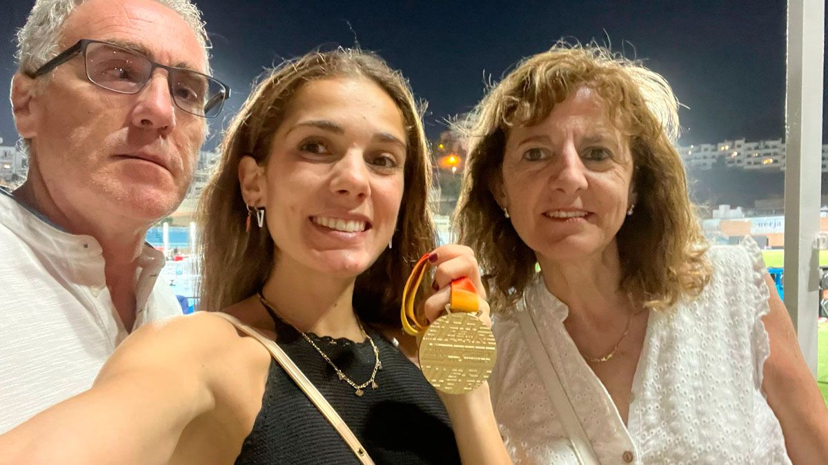 Marta García, con la medalla de oro en la mano junto a sus padres en el estadio de atletismo. | L.N.C.