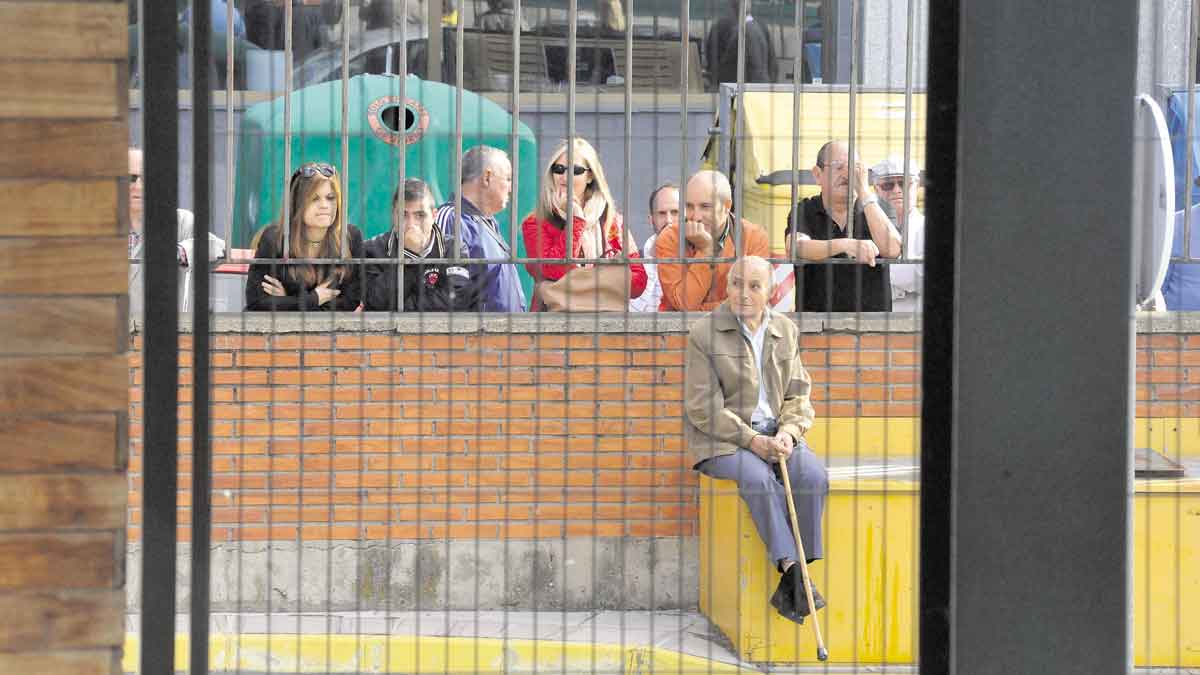 Varias personas expulsadas de la estación de León aguardan a la llegada del AVE al otro lado de una reja. | MAURICIO PEÑA Y DANIEL MARTÍN