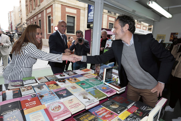 Virginia Barcones saludando a Héctor Escobar en la caseta de la Librería Universitaria y en presencia del alcalde José Antonio Diez. | CAMPILLO (ICAL)