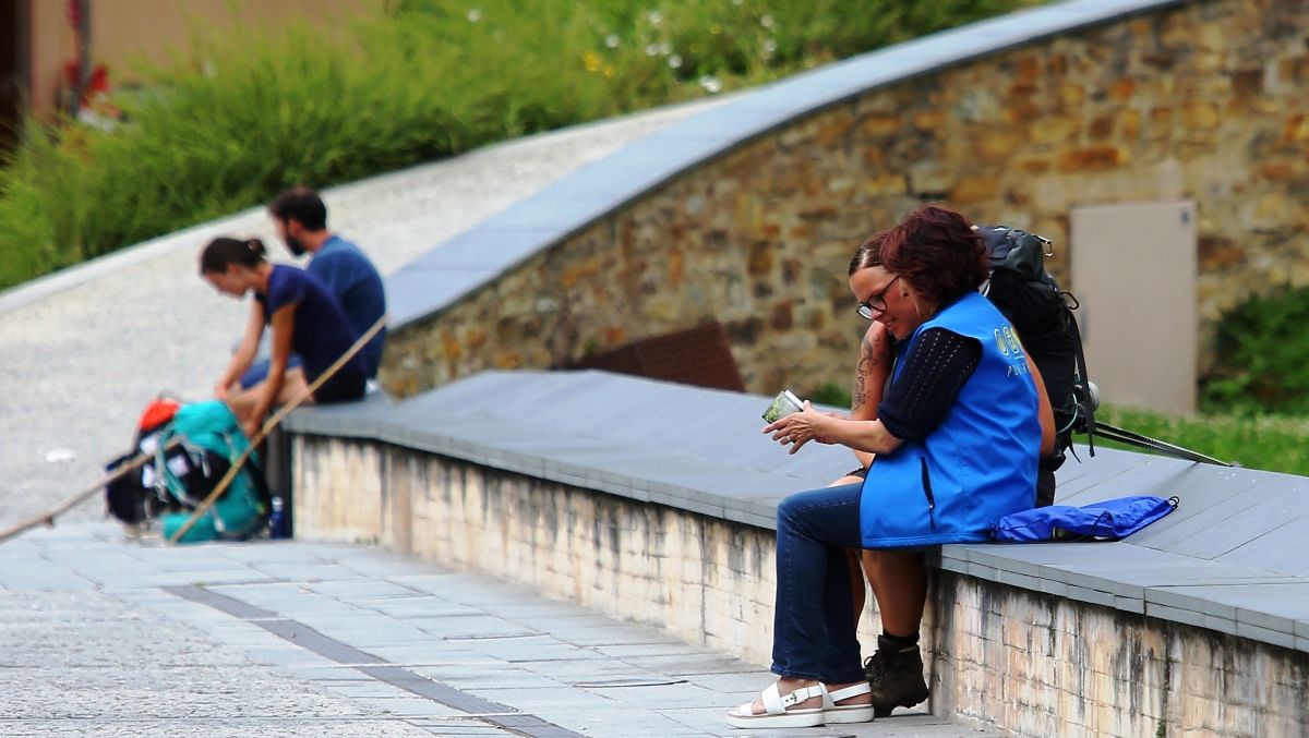 Peregrinos del Camino de Santiago reposan en el muro del foso del castillo de Ponferrada. | Ical