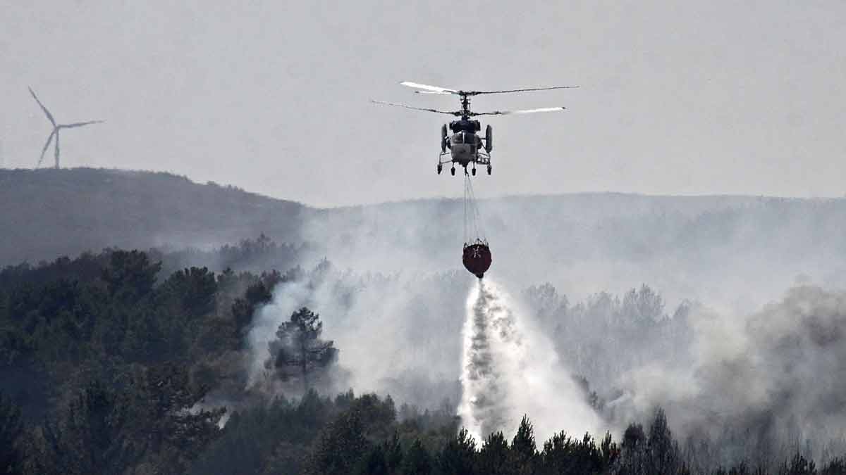 Un helicóptero intenta apagar las llamas del incendio. | ICAL