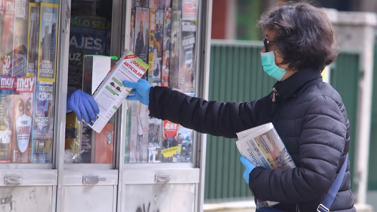 Una mujer compra el periódico en un kiosco. | ICAL Una mujer compra el periódico en un kiosco. | ICAL