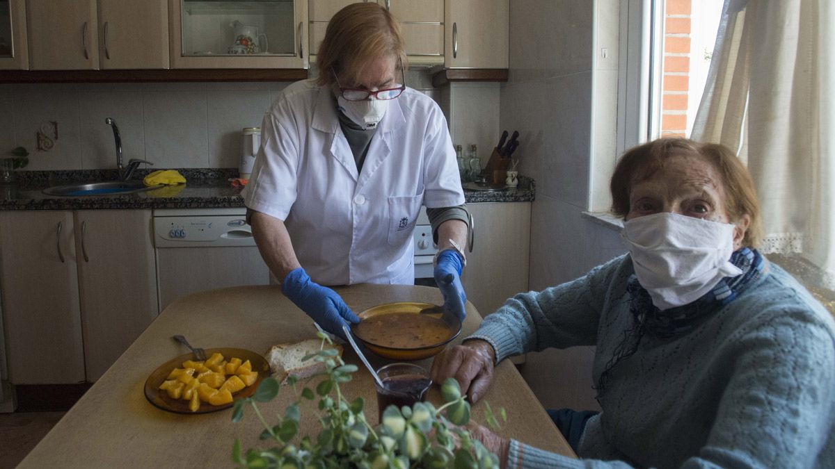 María Rosa Fernández, de 96 años, con la auxiliar Julia Arias, en su casa de Pobladura del Bernesga. | MAURICIO PEÑA