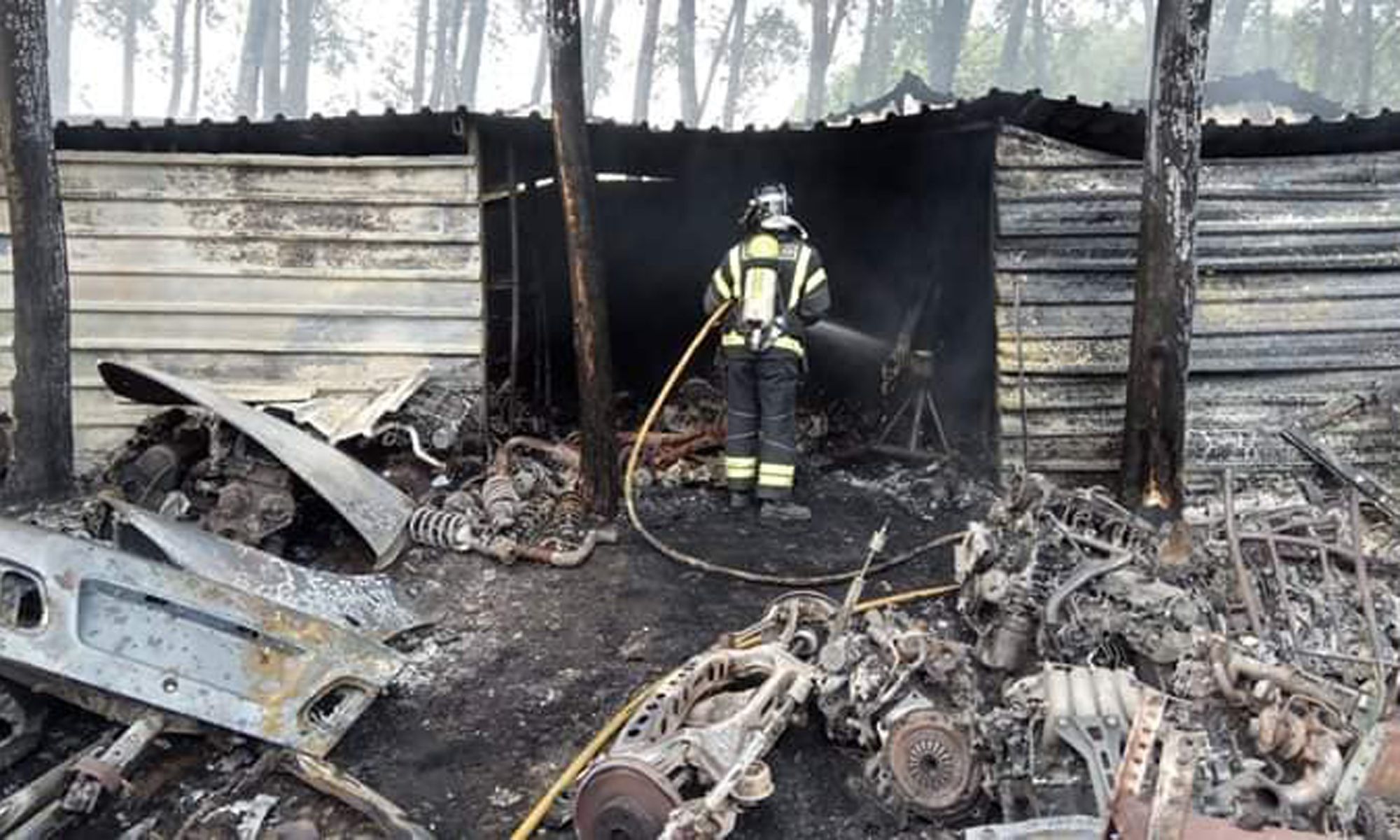 Uno de los bomberos repasa los rescoldos del fuego en la nave. | SPEIS