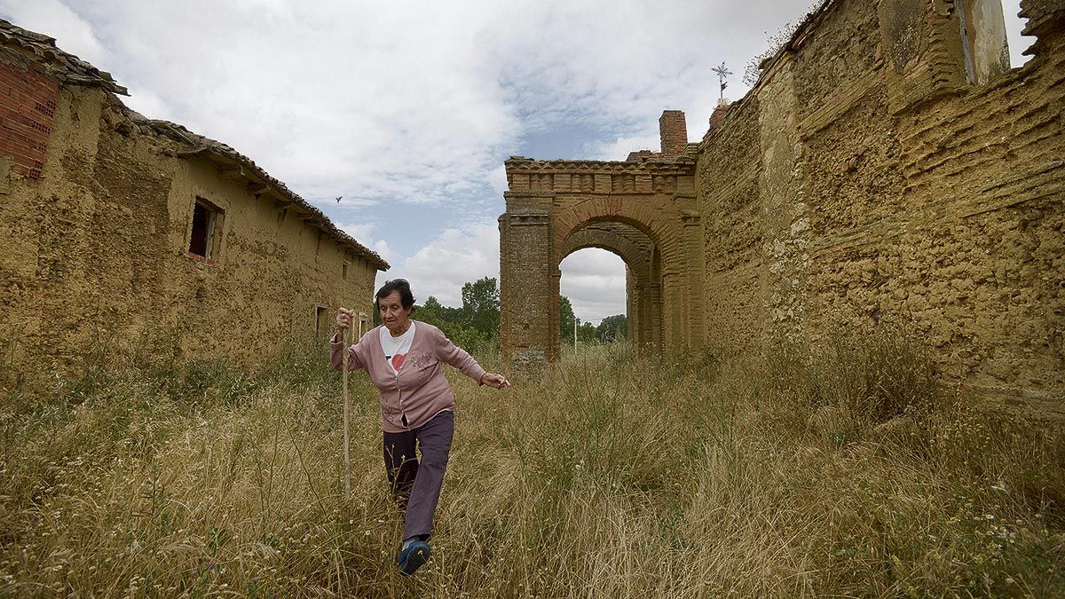 "Esto es una pena", repite Concha Martínez mientras recorre las calles de La Veguellina abriéndose camino entre la maleza. Es la única persona que vive todo el año en el pueblo. | REPORTAJE GRÁFICO: MAURICIO PEÑA