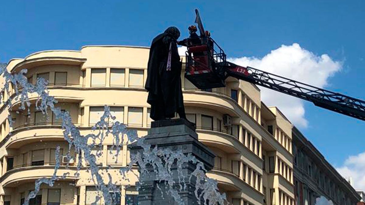 Un bombero coloca la bufanda y bandera de la Cultural a la estatua de Guzmán. | CYD