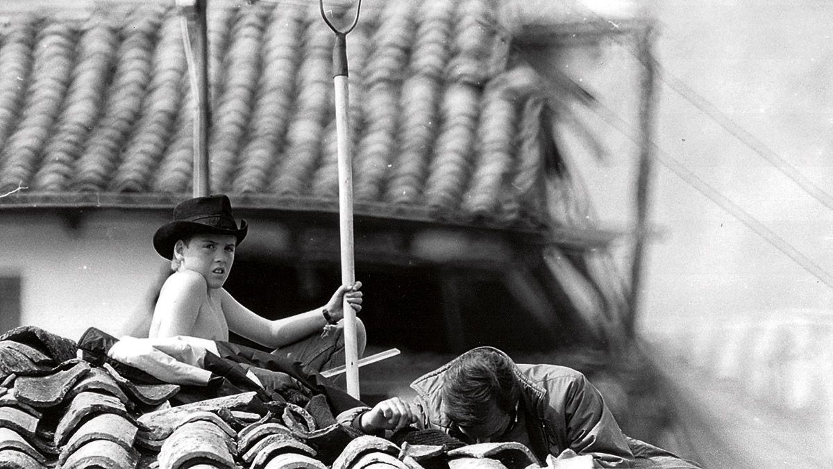 José Francisco Alonso, con solo 11 años, vigila desde el tejado los movimientos de las máquinas, a su lado, agachado, su tío Jesús. | MAURICIO PEÑA