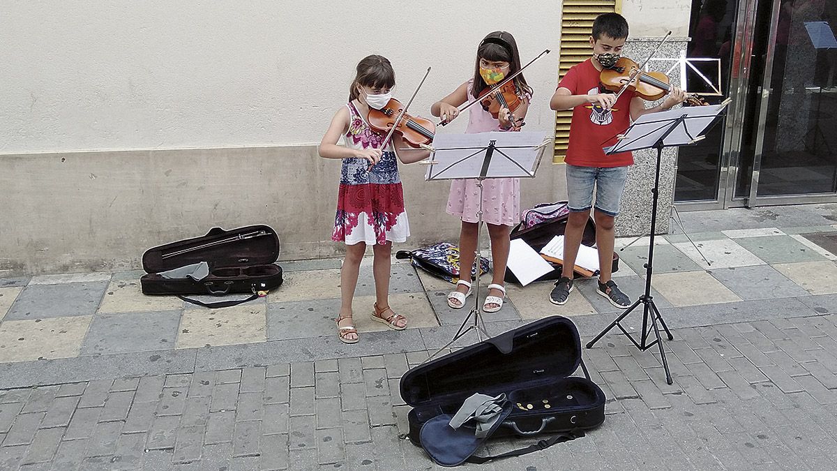 Tres alumnos de violín ofreciendo un concierto en cualquier rincón de Valencia de Don Juan, alumnos del curso que alegra los oídos de los coyantinos.