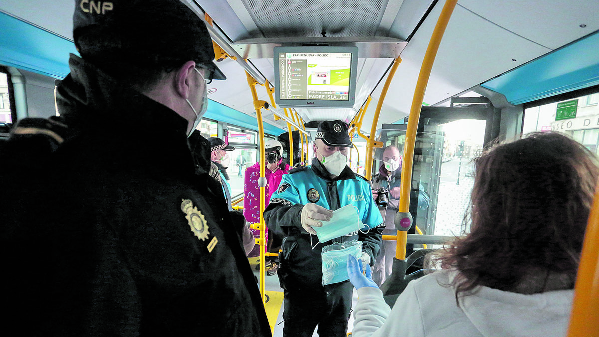 Un agente de la Policía Local de León reparte mascarillas a los pasajeros de un autobús. | CAMPILLO (ICAL)