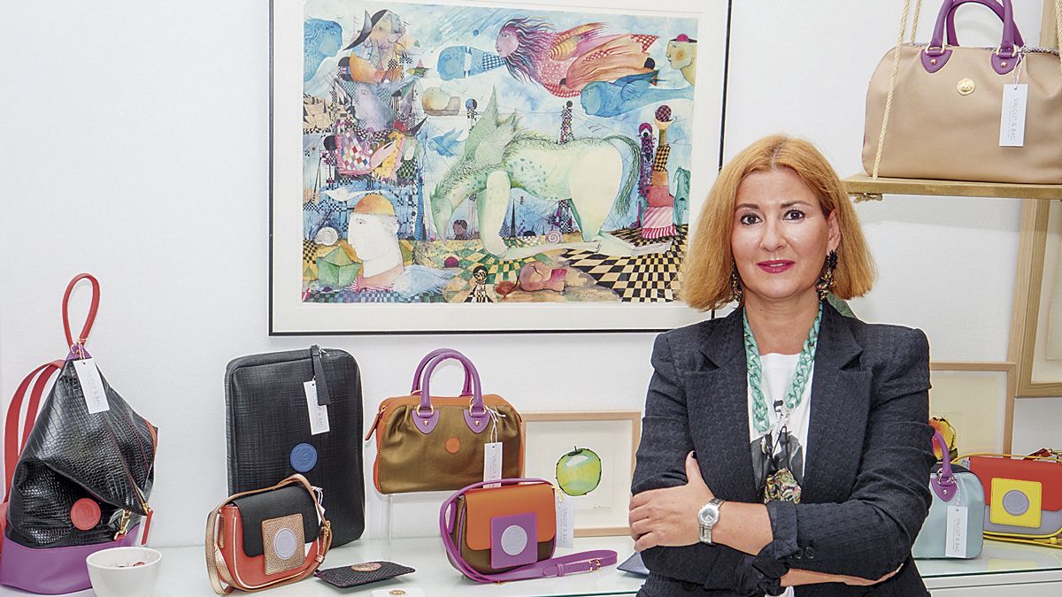 La diseñadora leonesa Begoña Gutiérrez Valcarce posa con algunos de los bolsos expuestos en la galería de arte Ármaga. | VICENTE GARCÍA