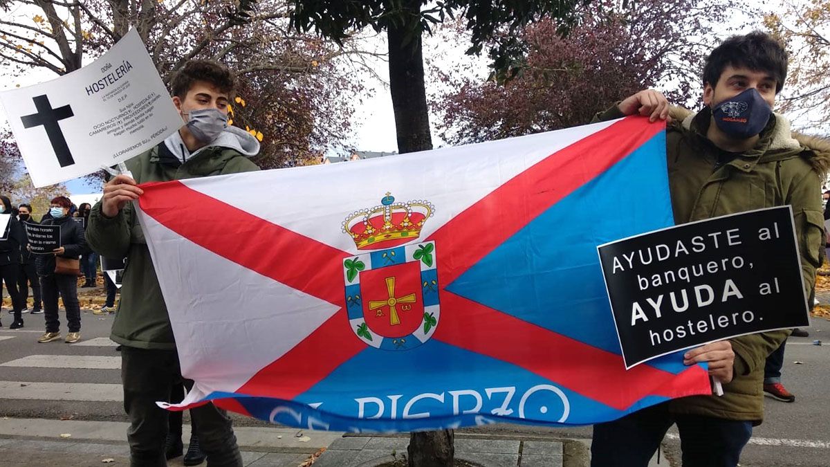 Dos de los hosteleros en la manifestación, con una bandera del Bierzo y pancartas reivindicativas. | L.N.C.