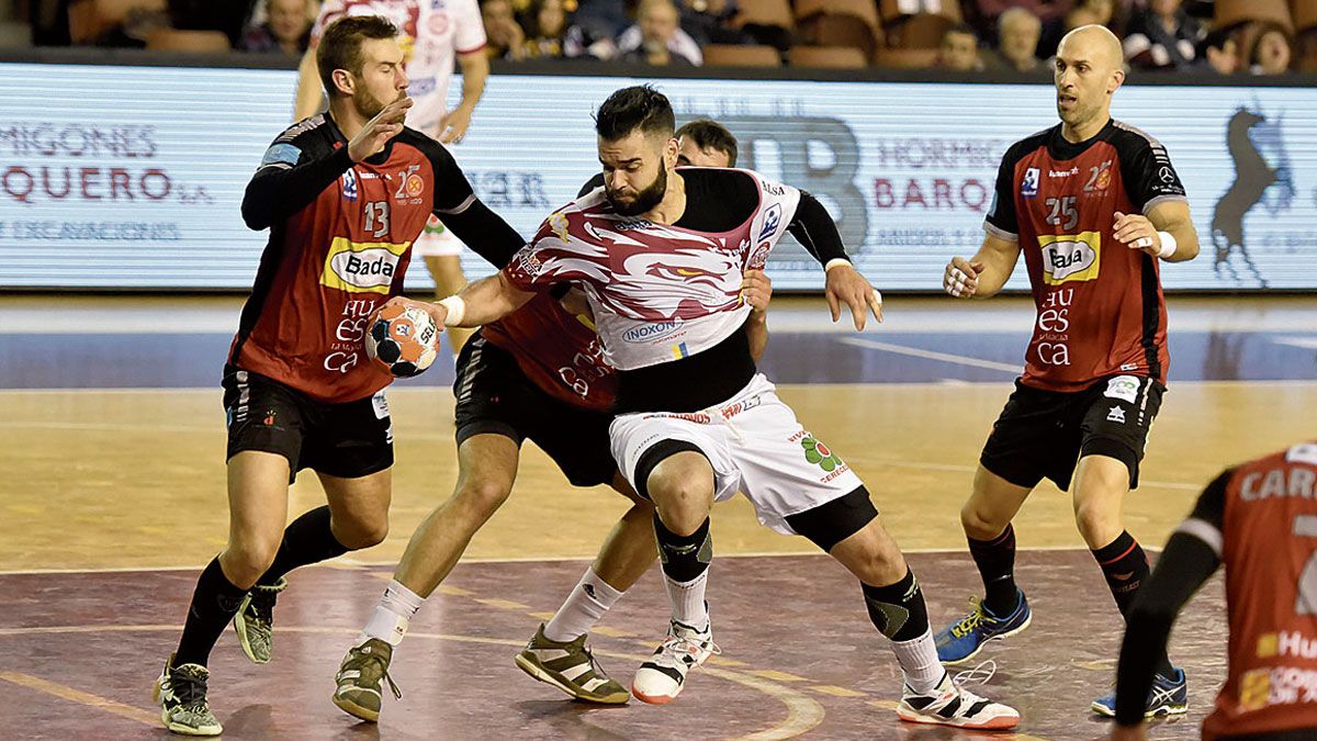 Marchán intenta zafarse de dos defensores del Huesca. | SAÚL ARÉN