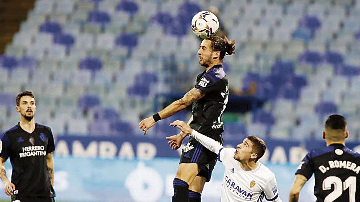 Adri Castellano despeja un balón de cabeza ante la mirada de un atacante zaragocista. | LALIGA