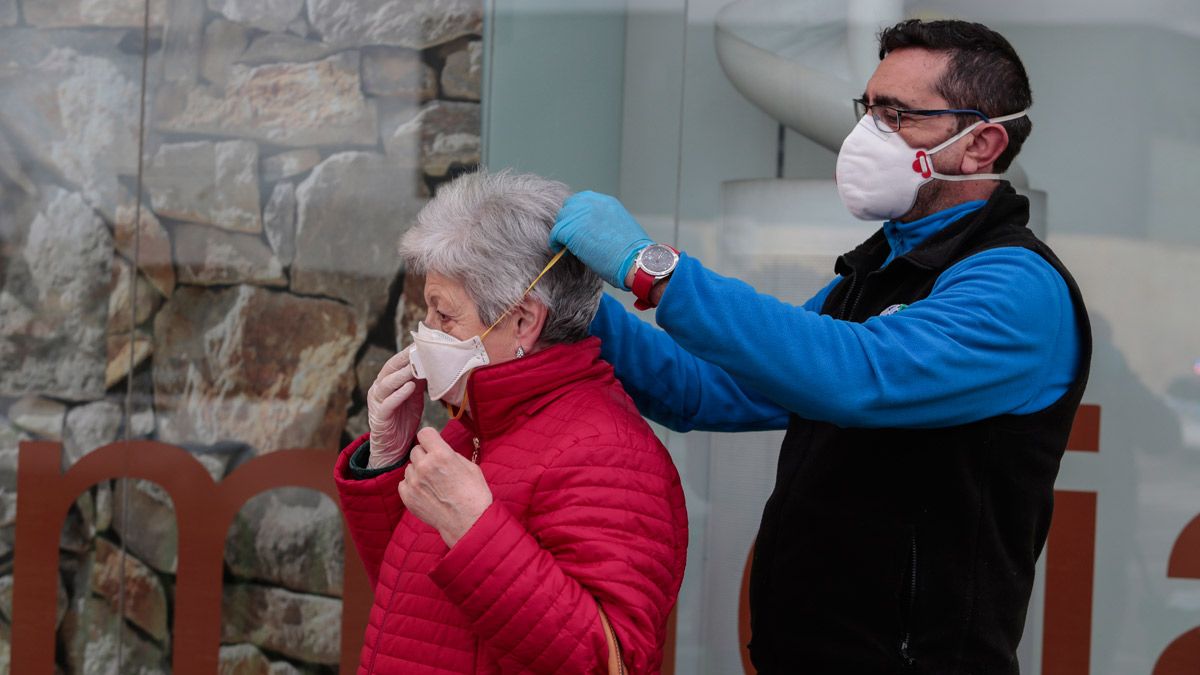 Un hombre ayuda a una leonesa a colocarse bien su mascarilla. | ICAL