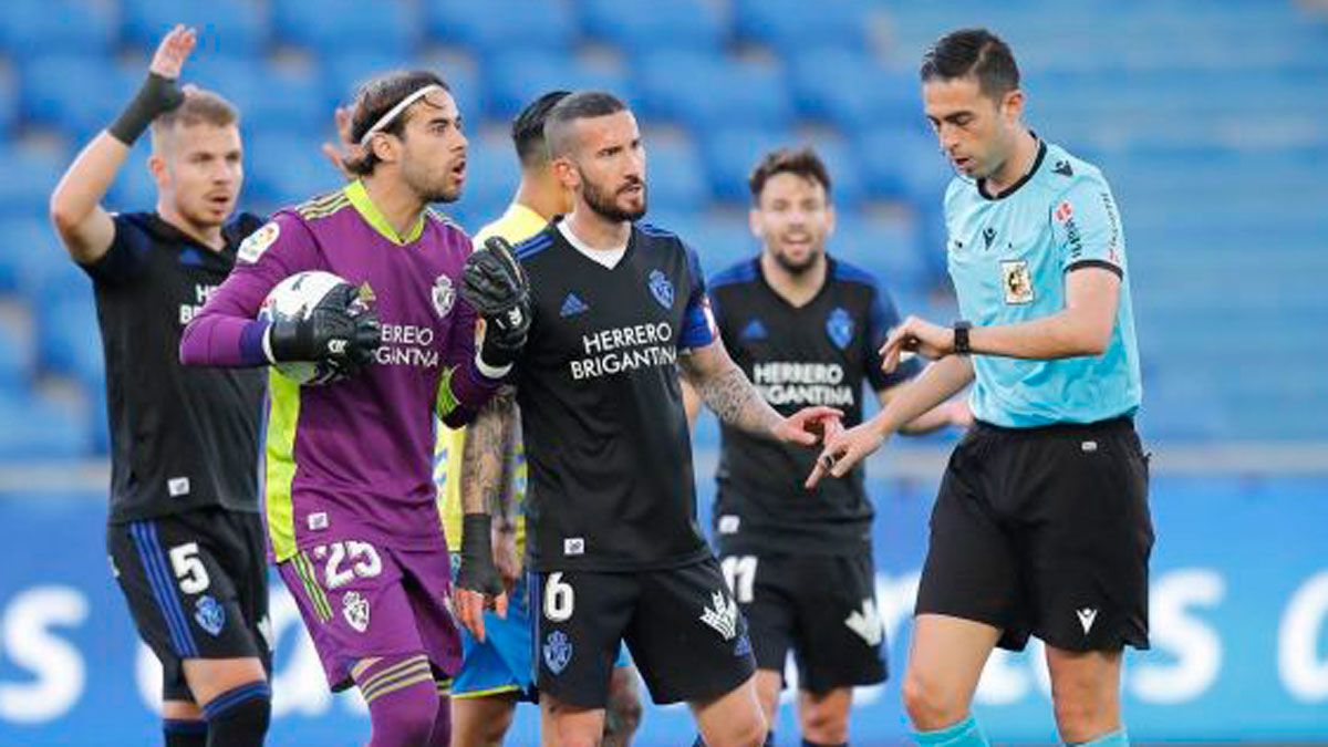 Los jugadores de la Deportiva protestan a Vicandi Garrido la señalización del penalti que supuso el 1-0. | LALIGA