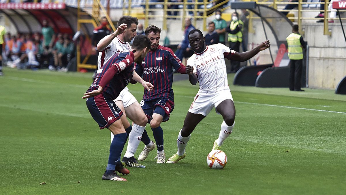 Ketu encara a dos rivales del Extremadura durante su partido en León. | SAÚL ARÉN
