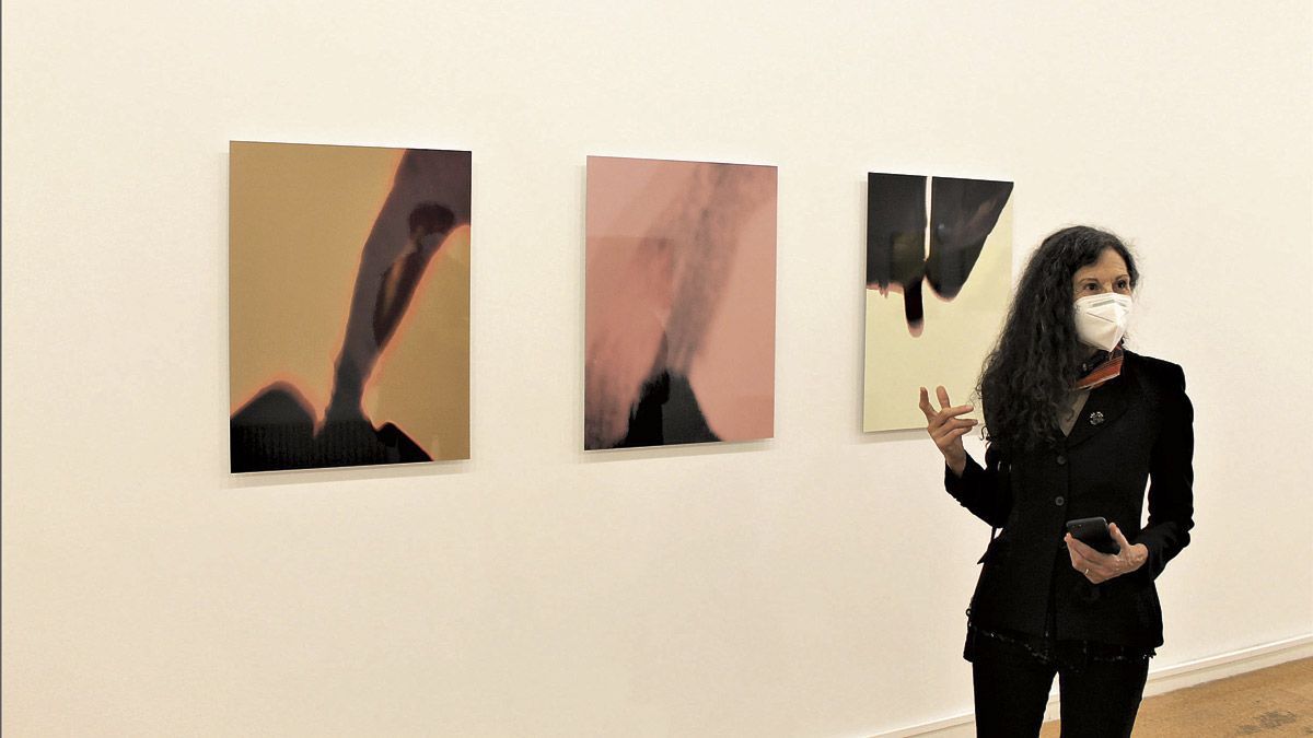 La artista Pilar Cossío junta a tres de las obras que conforman la muestra ‘Illuminations’ que ha traído a León. | ULE