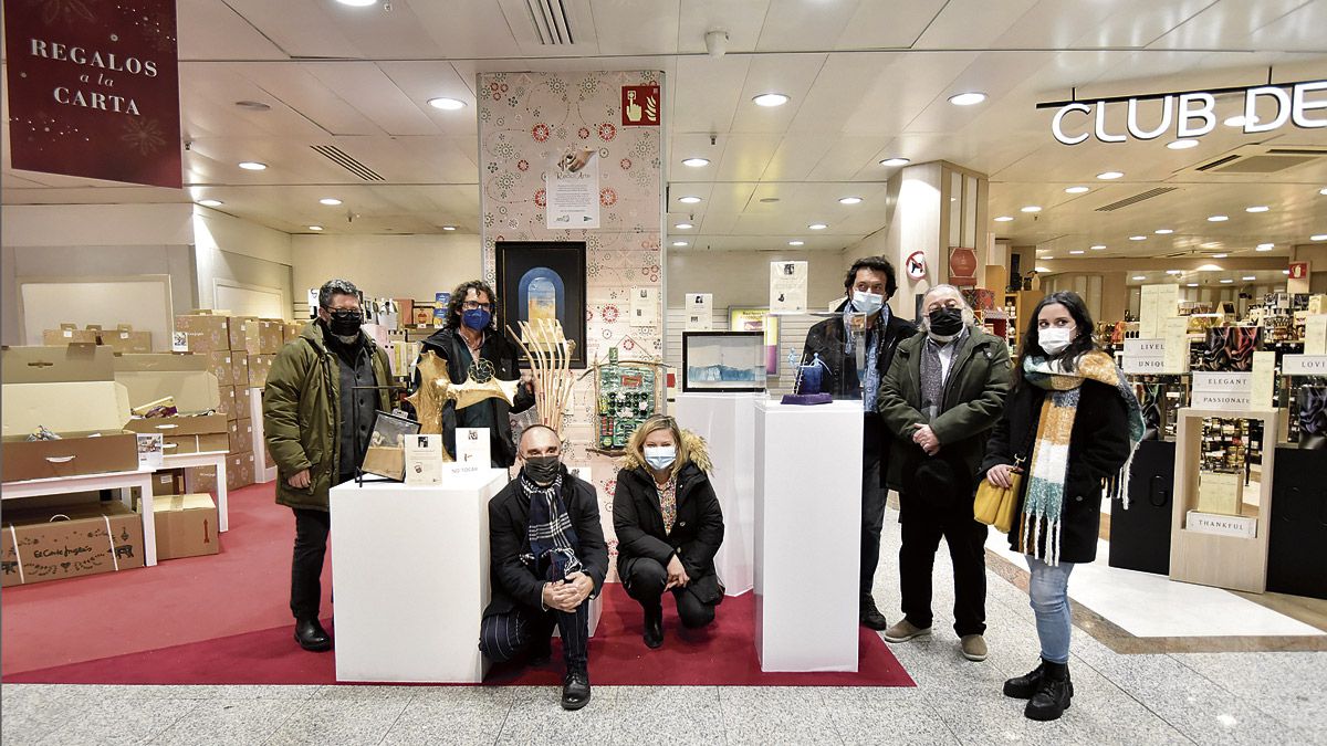 Los artistas participantes en esta muestra solidaria posan con sus obras en la planta semisótano de El Corte Inglés de León. | SAÚL ARÉN