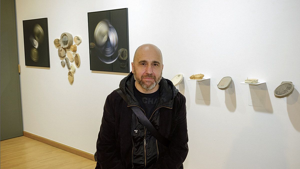 El artista asturiano Paco Redondo junto a algunas de las piezas y fotografías que se exponen en la galería Espacio_ E. | VICENTE GARCÍA