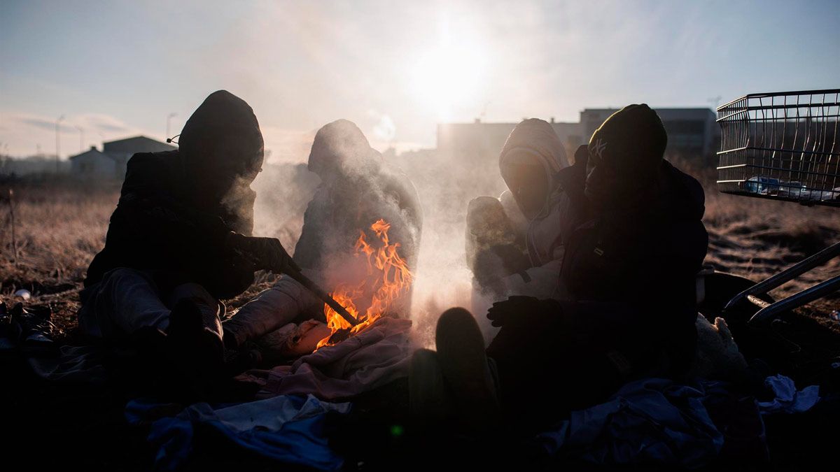 Un grupo de personas ghanesas preparan una hoguera en Medyka, frontera de Polonia con Ucrania. | EP