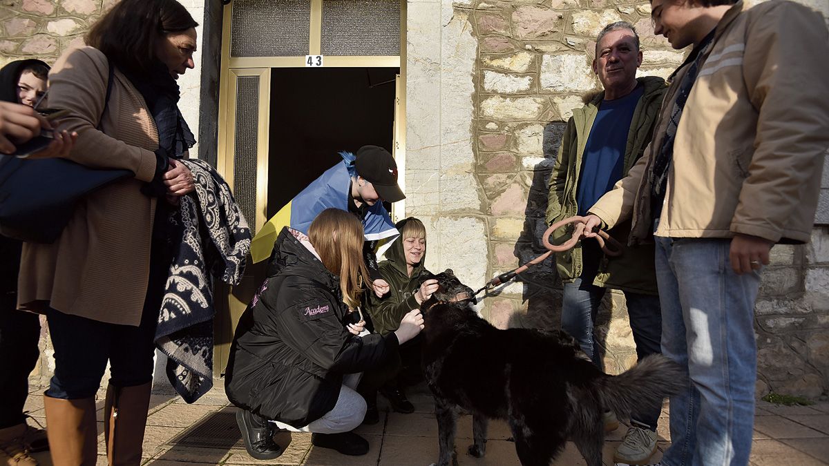 Vika, Sonnia y Olona, con la bandera de Ucrania, acarician un perro de un vecino de Villamanín, ellas también han traído a Gvro. | SAÚL ARÉN