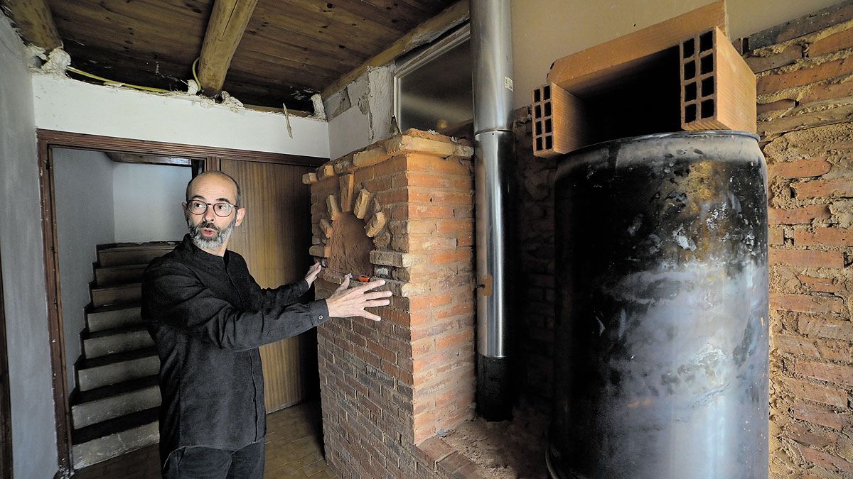 El lutier afincado en la Valduerna muestra el sistema de calefacción que está instalado en su casa, aún sin finalizar, "falta mucho barro", explica.  | MAURICIO PEÑA