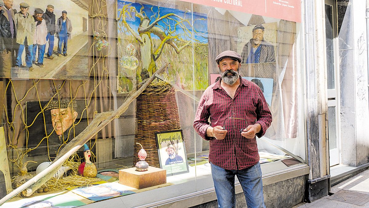 Cisneros posa ante el escaparate de Conde Rebolledo que muestra su obra durante este mes de julio | V. García