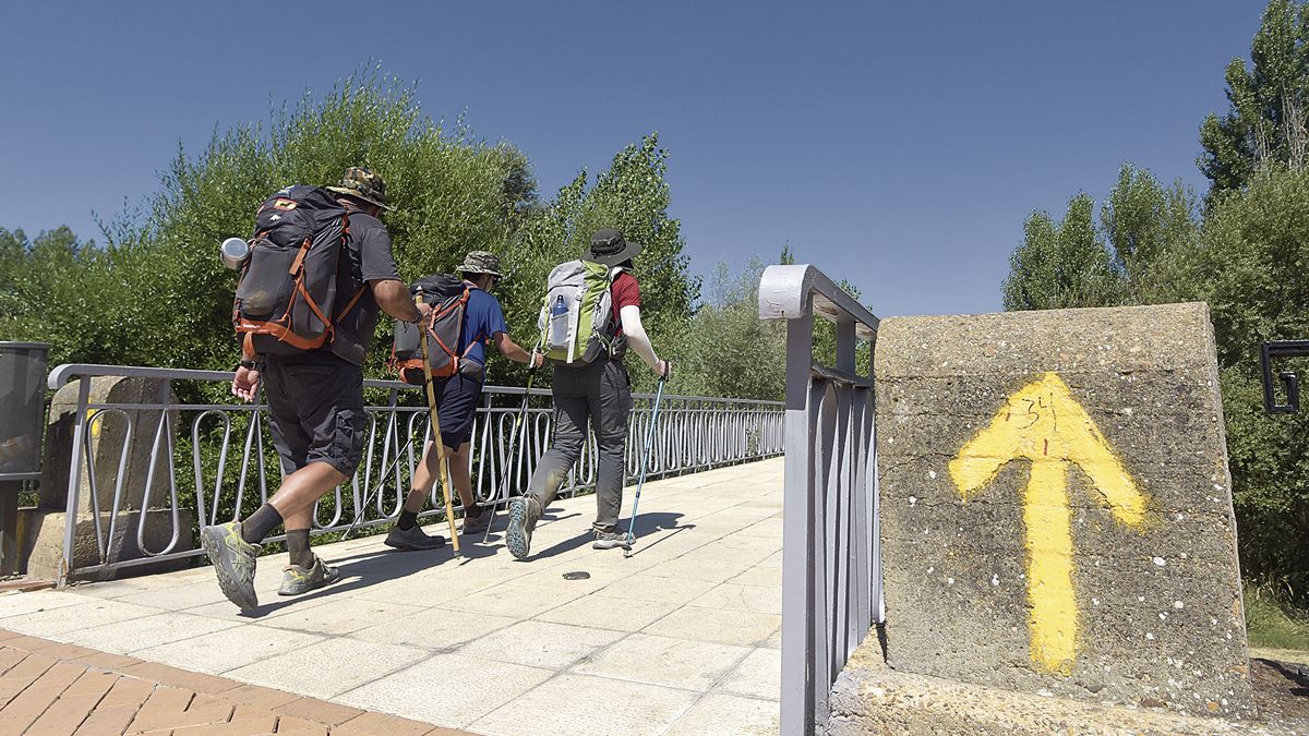Un grupo de peregrinos en la pasarela de Puente Castro, justo después del punto de información del Ayuntamiento de León. | SAÚL ARÉN