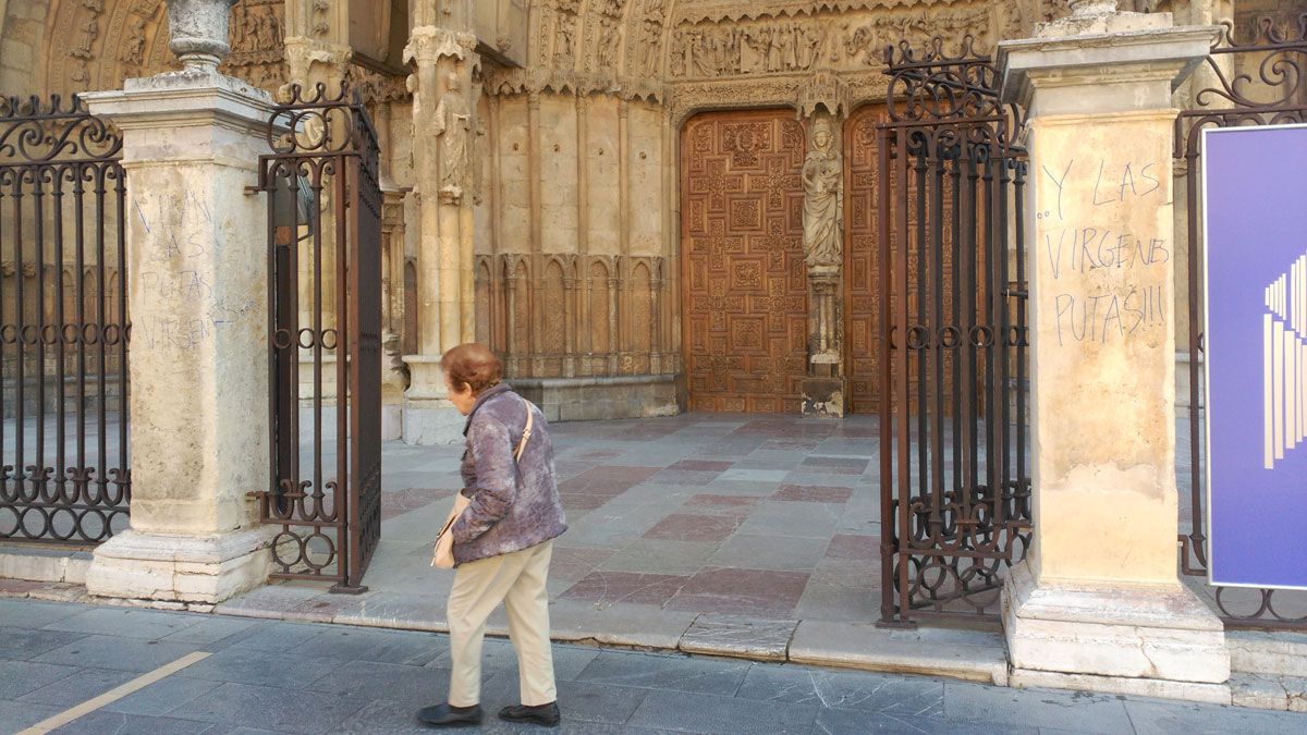 Una mujer pasea frente a la entrada principal a la Catedral, en la que se observan las dos pintadas.