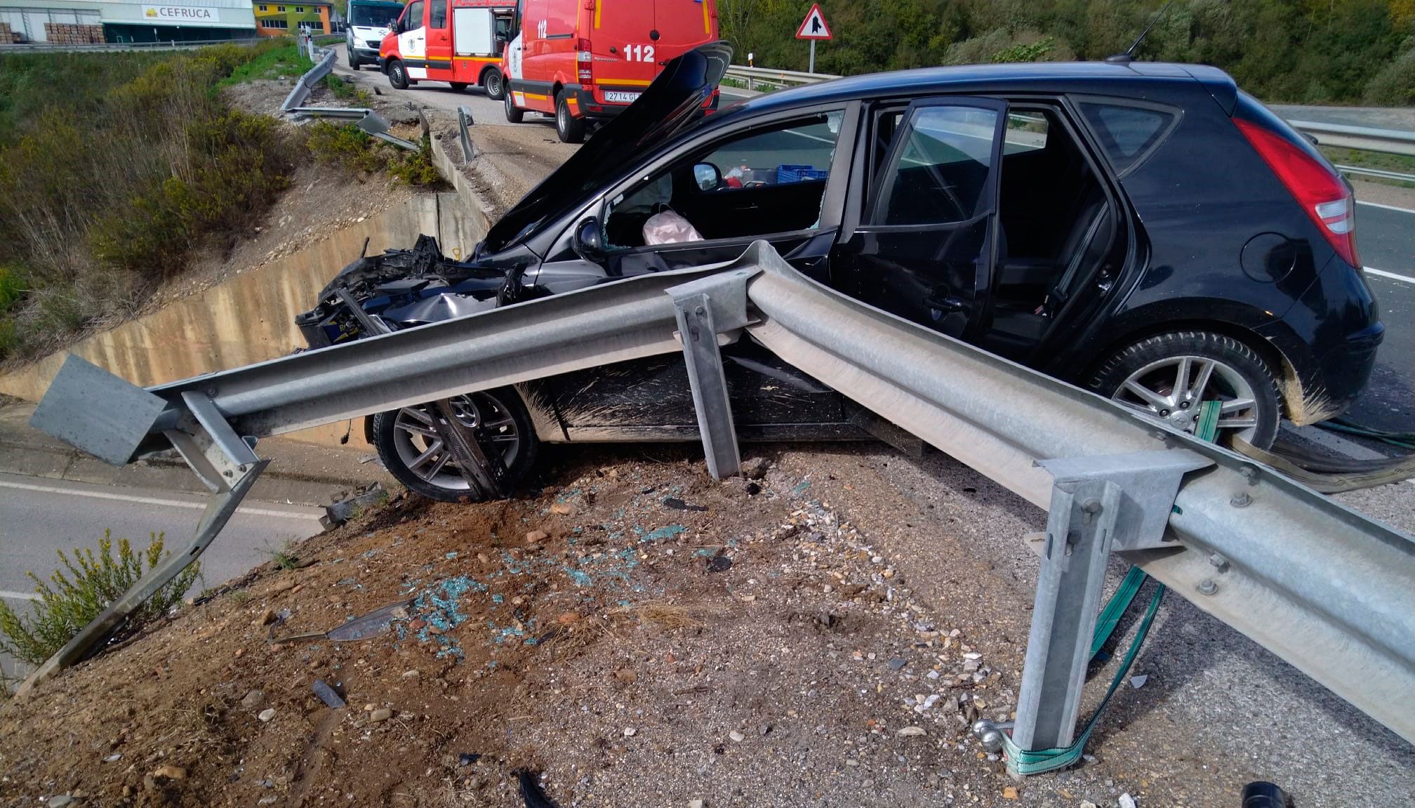 El coche quedó casi colgado del terraplén tras llevarse por delante el guarda rail. | BOMBEROS PONFERRADA