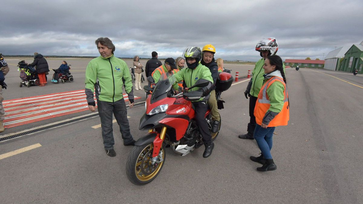 Un motero sube a su moto a uno de los usuarios del CRE de San Andrés del Rabanedo. | SAÚL ARÉN