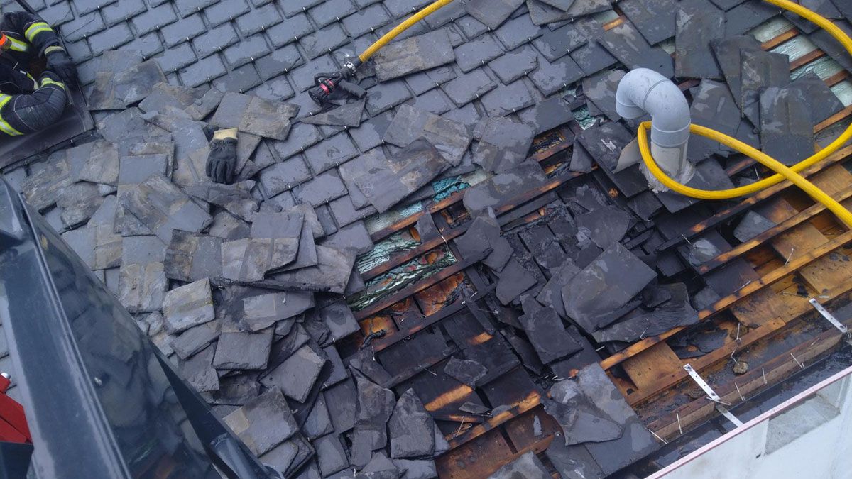 Trabajos en el tejado de la vivienda donde se produjo el fuego. | BOMBEROS PONFERRADA