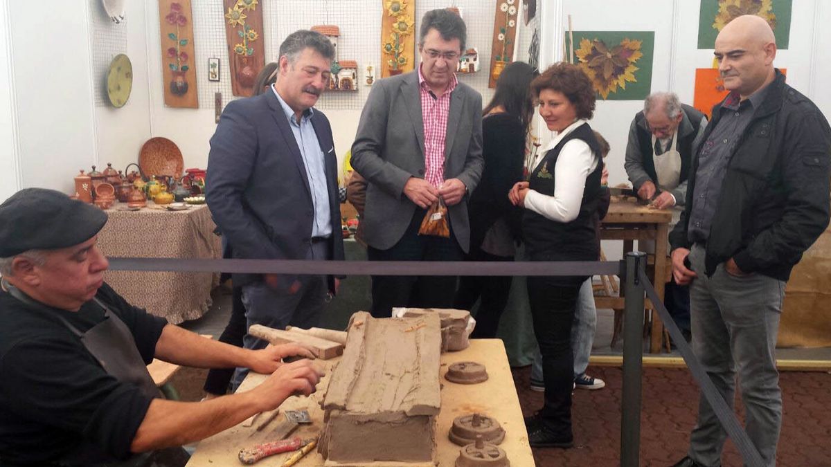 Ángel Calvo y Juan Martínez Majo observan a uno artesano modelador en el recinto del mercado. | L.N.C