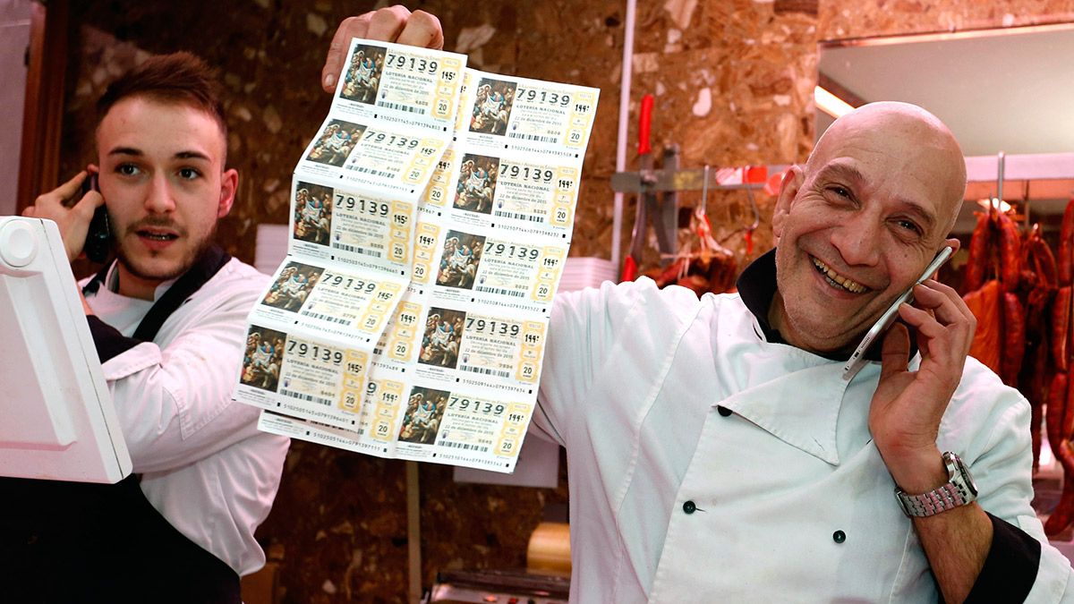 Los carniceros Juan Carlos Fernández (D) y Rubén Fernández (I), muestran los décimos premiados con 2000 euros cada uno por ser el número anterior al gordo de la Lotería de Navidad. | ICAL