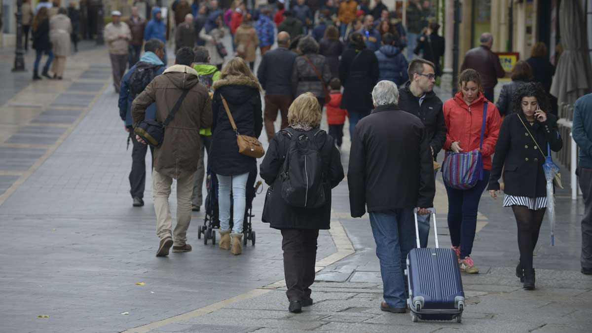 Una pareja de turistas se dispone a subir por la calle Ancha de la capital leonesa con su maleta. | MAURICIO PEÑA