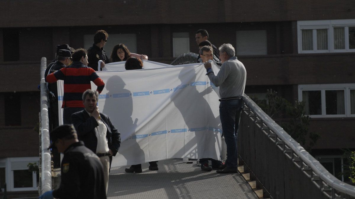 Una par de sábanas ocultan los restos mortales de Isabel Carrasco tras haber sido asesinada en mitad de una pasarela sobre el Bernesga. | MAURICIO PEÑA