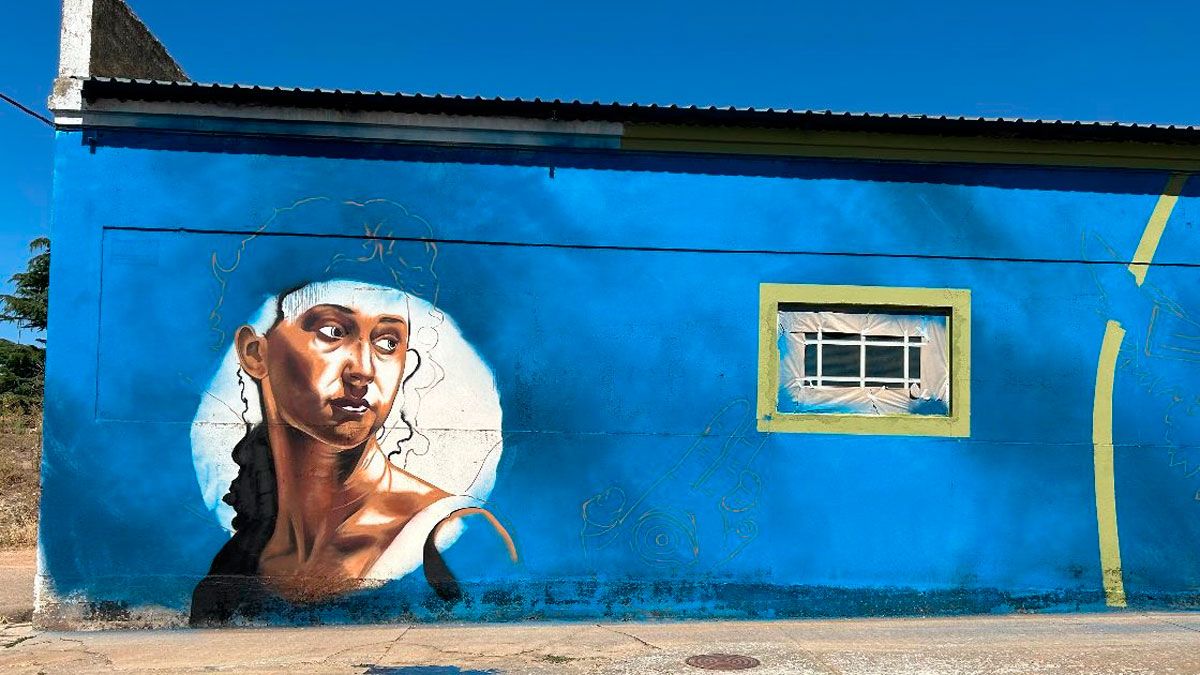 Uno de los artistas trabajando en su mural de la carretera de Alija del Infantado, en una nave industrial. | ABAJO