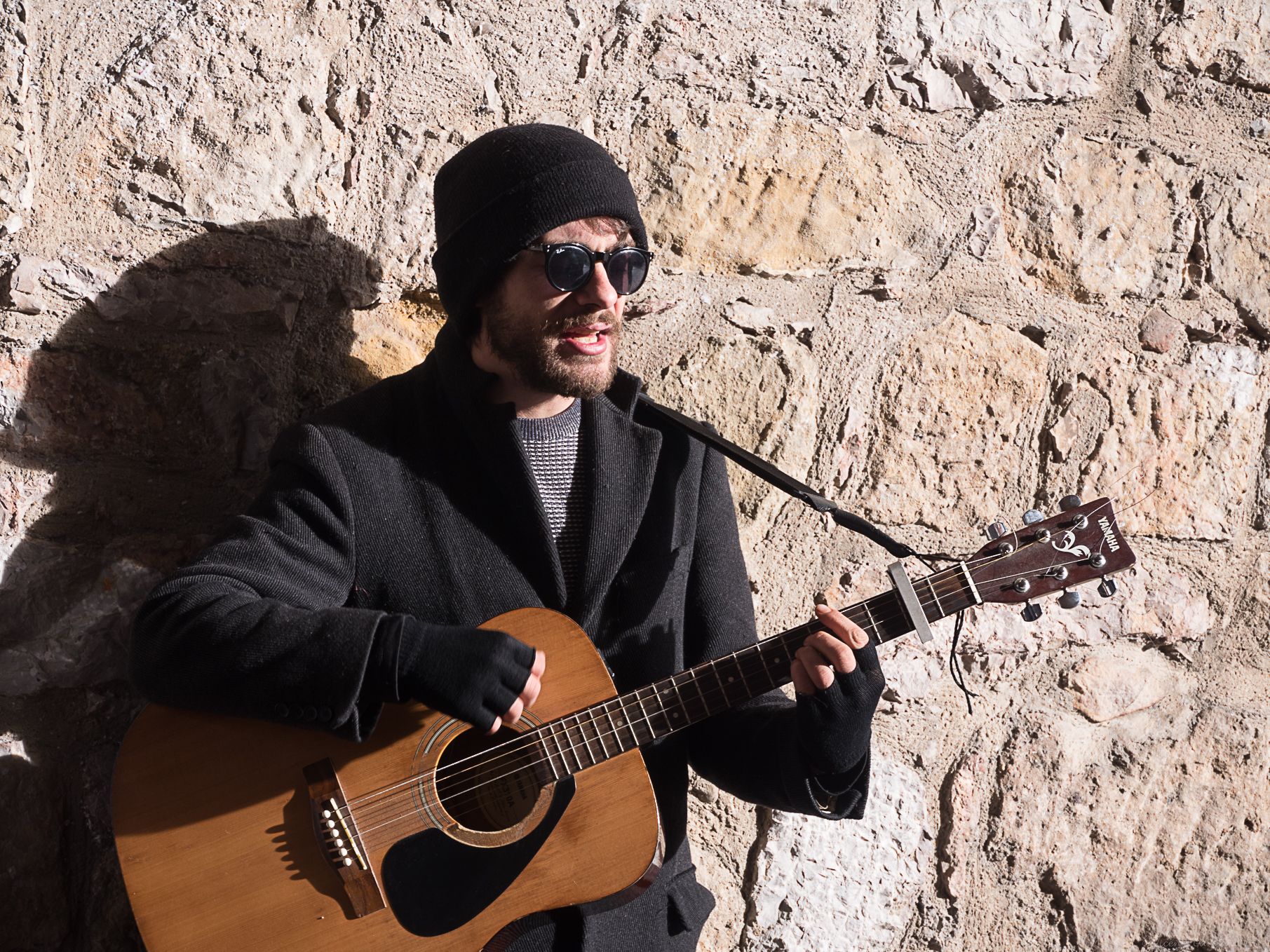 Guitarra, gafas y gorro para aliviar el frío componen el atuendo del artista leonés en una de sus jornadas tocando en la calle. | VICENTE GARCÍA