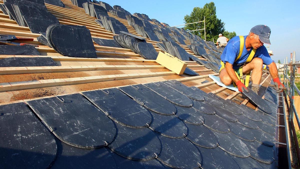 Un trabajador de la construcción coloca un tejado de pizarra en Ponferrada. | C. SÁNCHEZ (ICAL) Un trabajador de la construcción coloca un tejado de pizarra en Ponferrada. | C. SÁNCHEZ (ICAL)