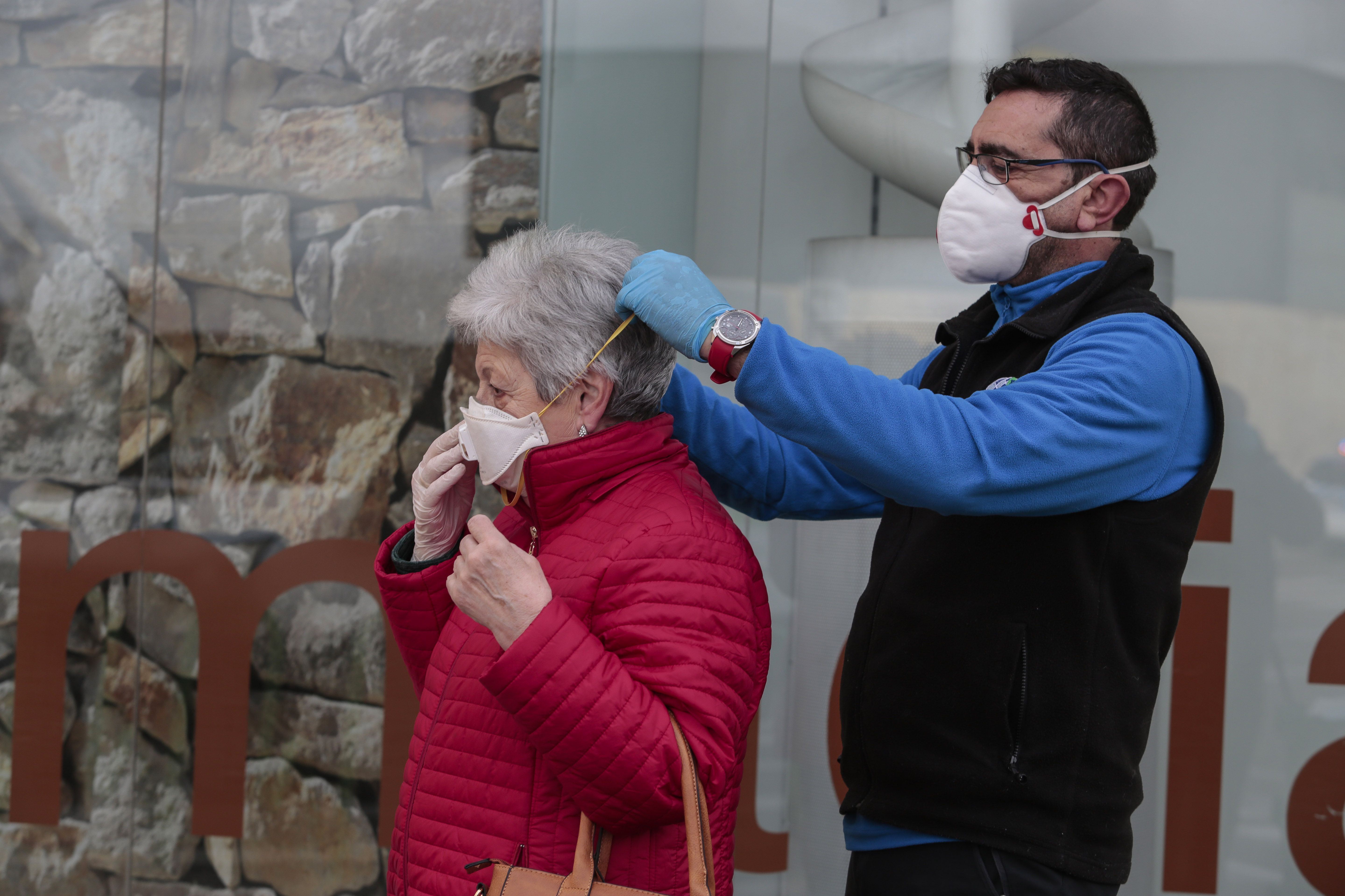 Un hombre ayuda a una mujer a colocarse una mascarilla en León. | CAMPILLO (ICAL)