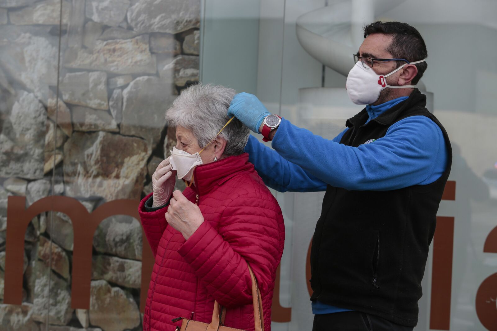 Un hombre ayuda a una mujer a colocarse una mascarilla en León. | CAMPILLO (ICAL)