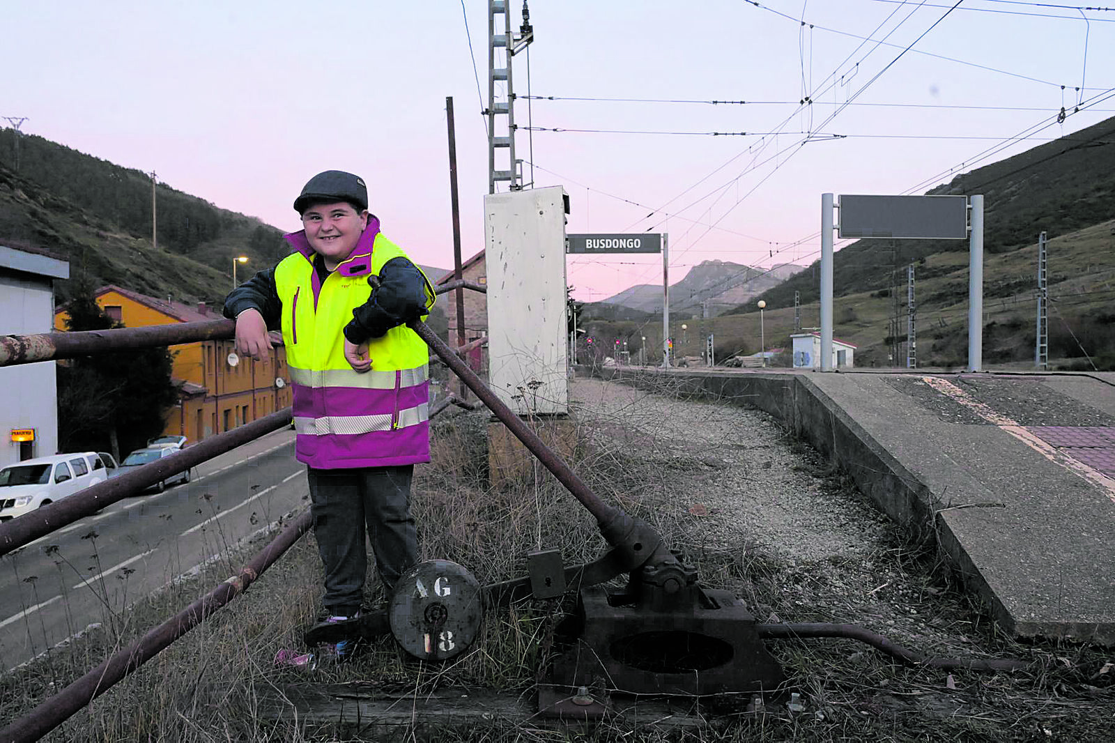 Izan, vestido de ferroviario, posa ante su estación preferida, la de Busdongo, pues sabe al dedillo la rica historia que la adorna. | MAURICIO PEÑA