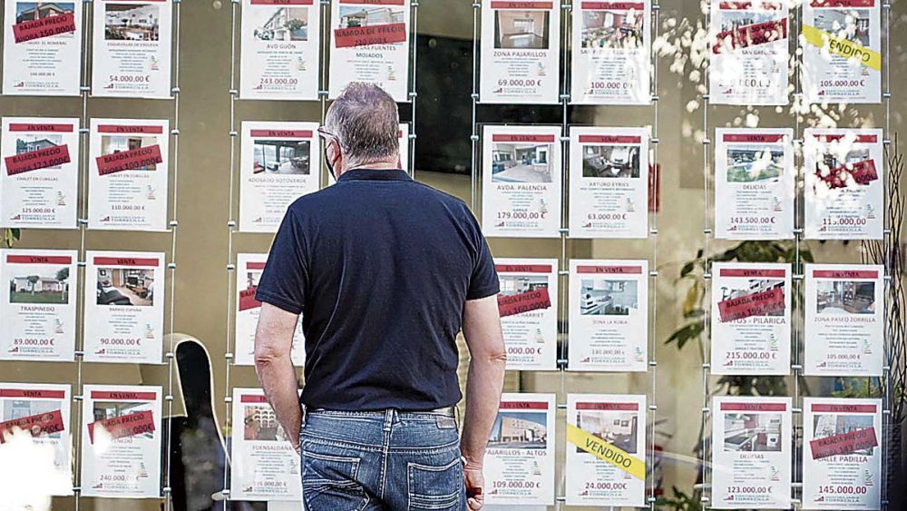 Un hombre observa el escaparate de viviendas de una inmobiliaria. | ICAL