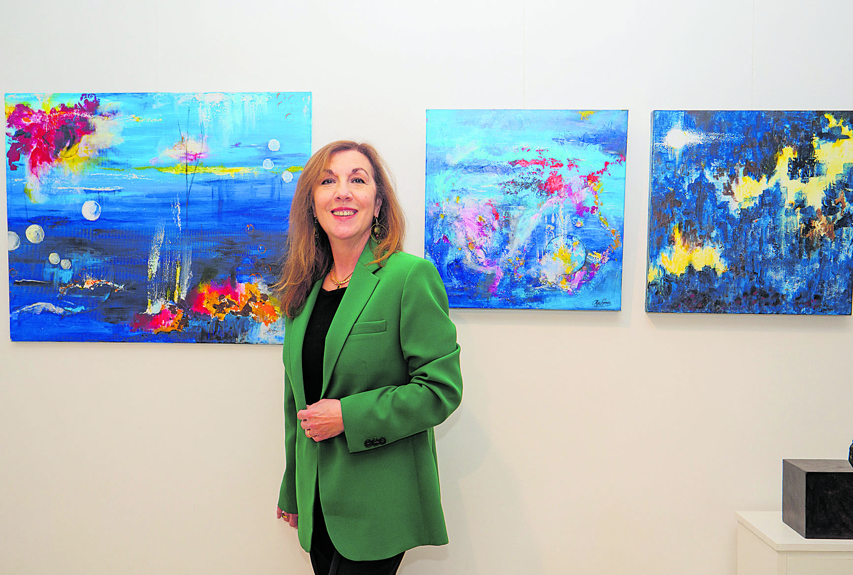 Olga Gómez posa ante tres obras de la exposición ‘Bajo las luces’ que estos días puede visitarse en la galería Alemi de la capital. | VICENTE GARCÍA