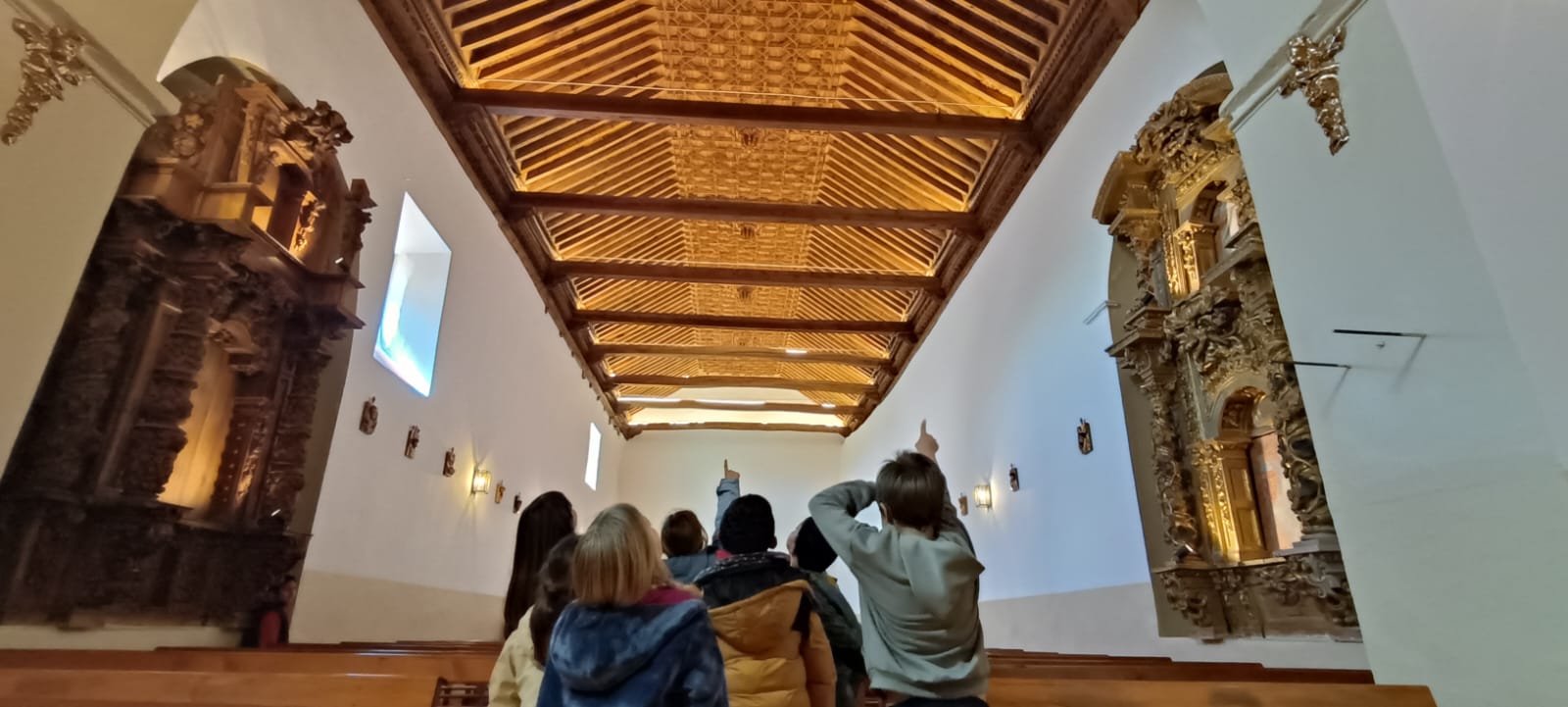 Los alumnos observando el nuevo artesonado mudéjar de la iglesia. | L.N.C.